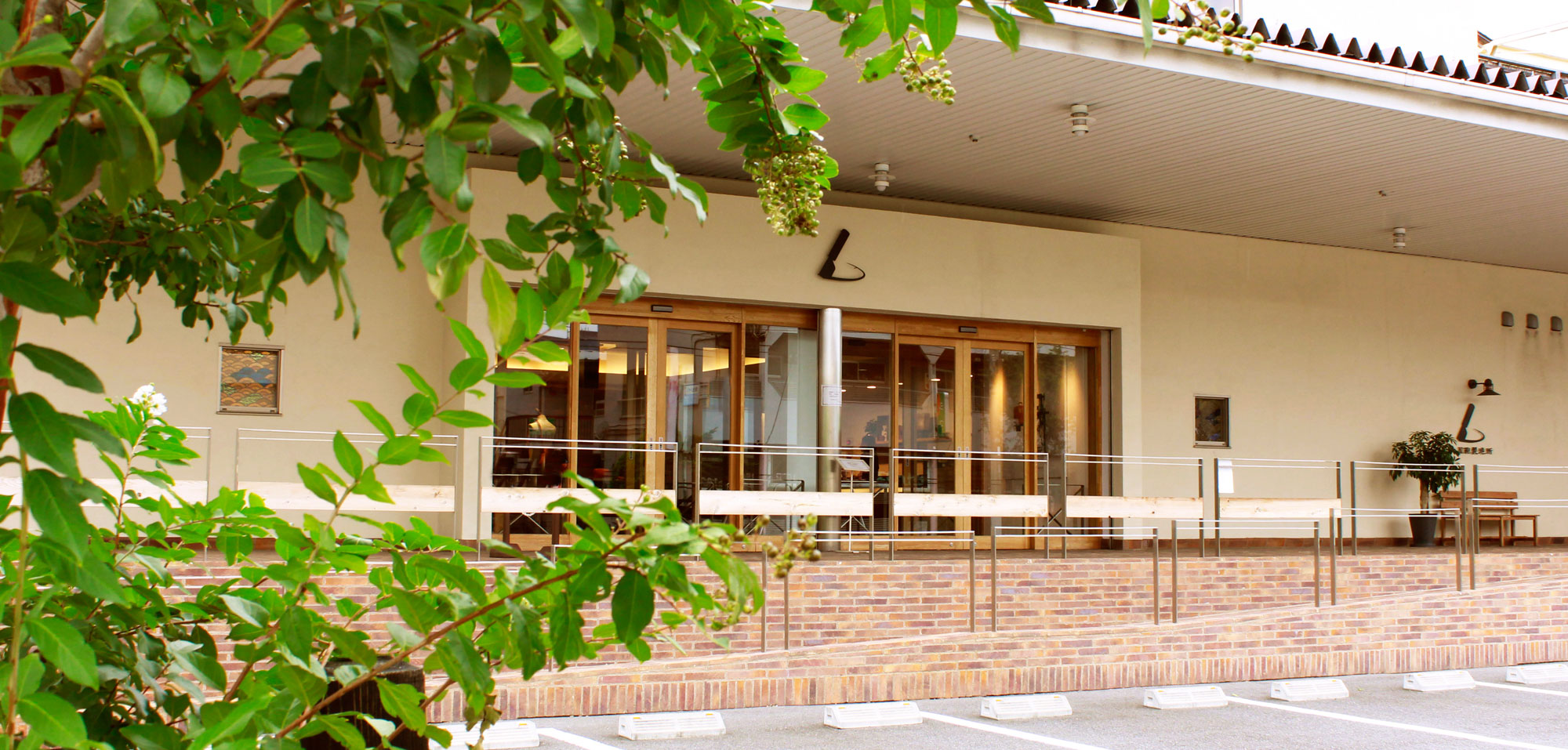 Modern building exterior with large windows and greenery in the foreground.